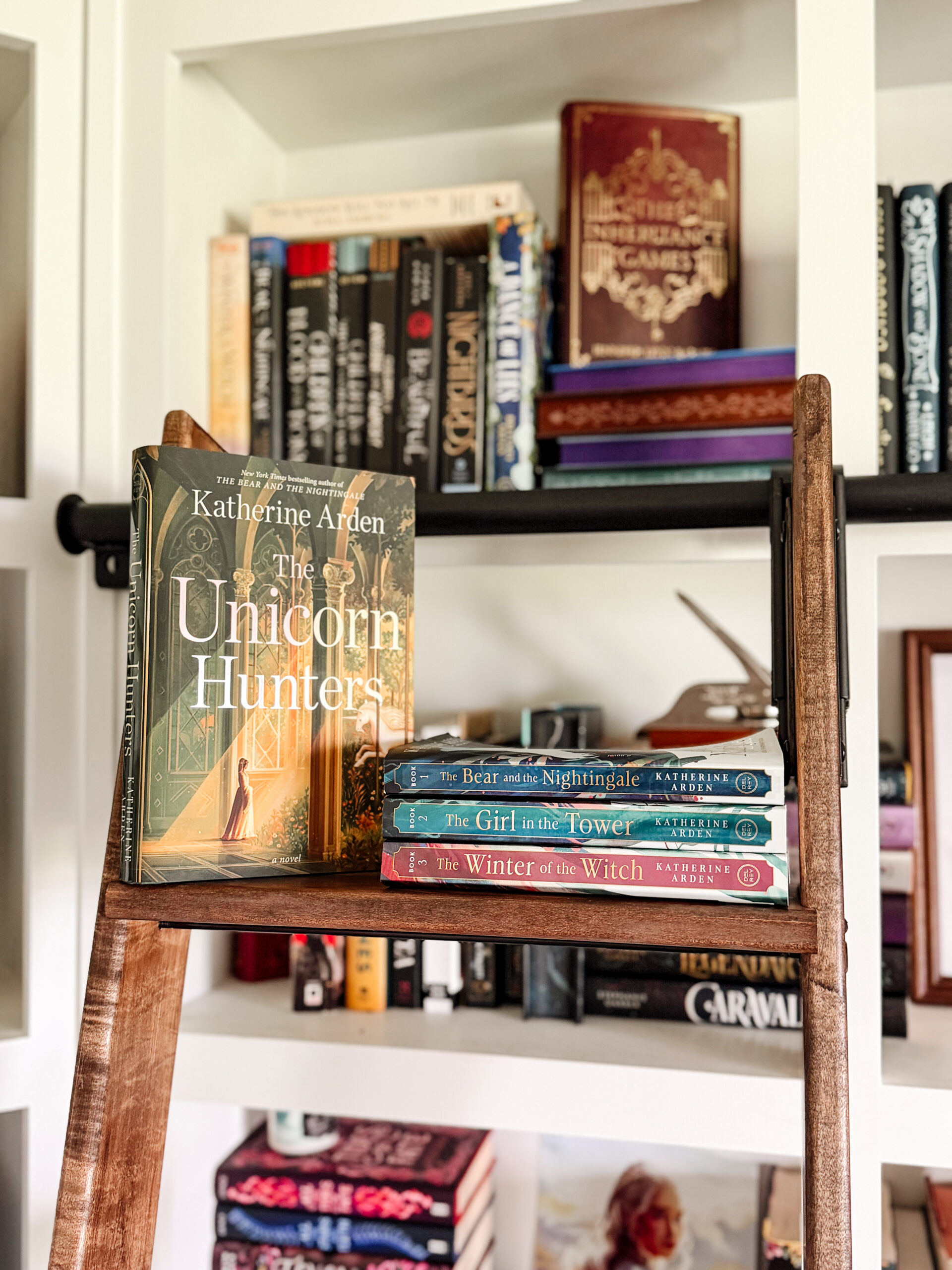 The Unicorn Hunters Book on a book ladder with bookstack of Katherine Arden books